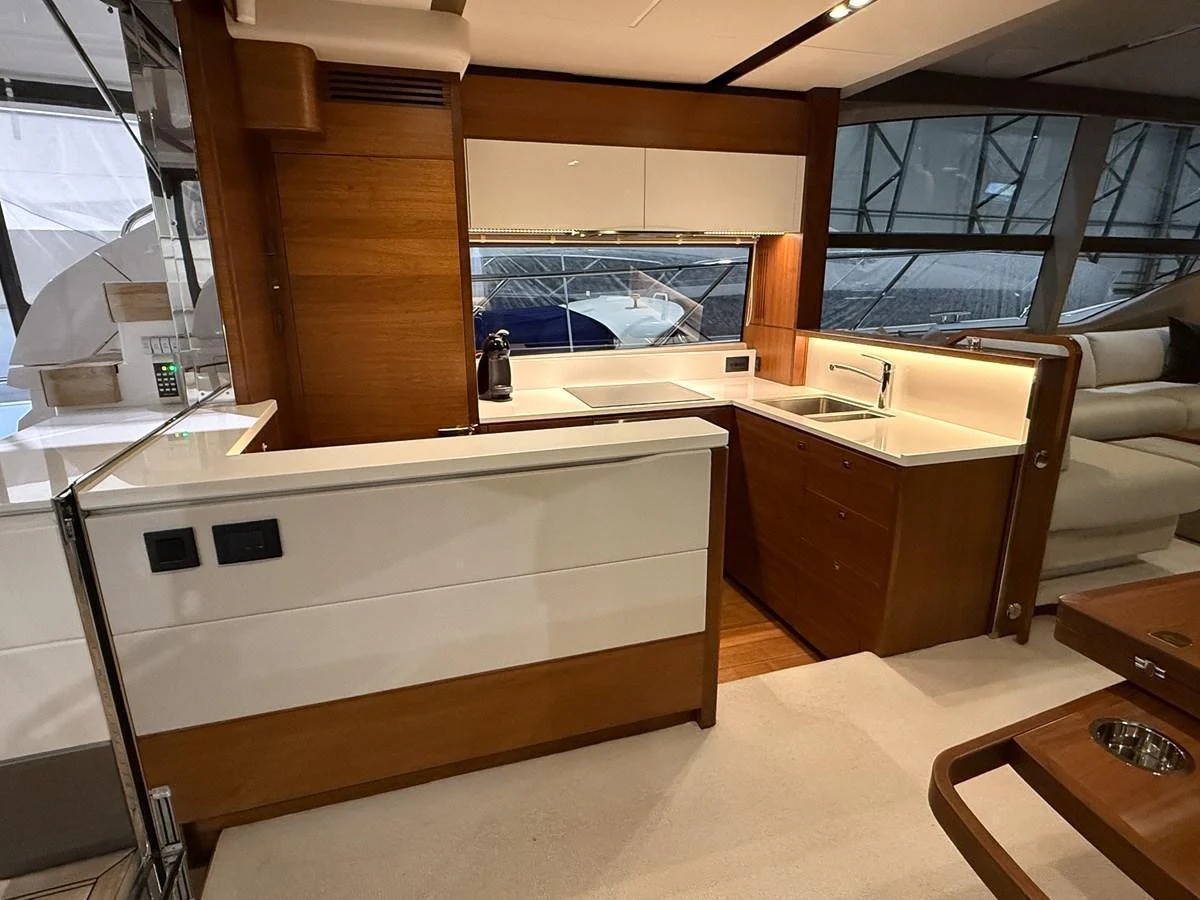 The yacht's galley features modern wood cabinetry and sleek white countertops, creating a stylish and functional space. aboard PRINCESS 70 Yacht for Sale