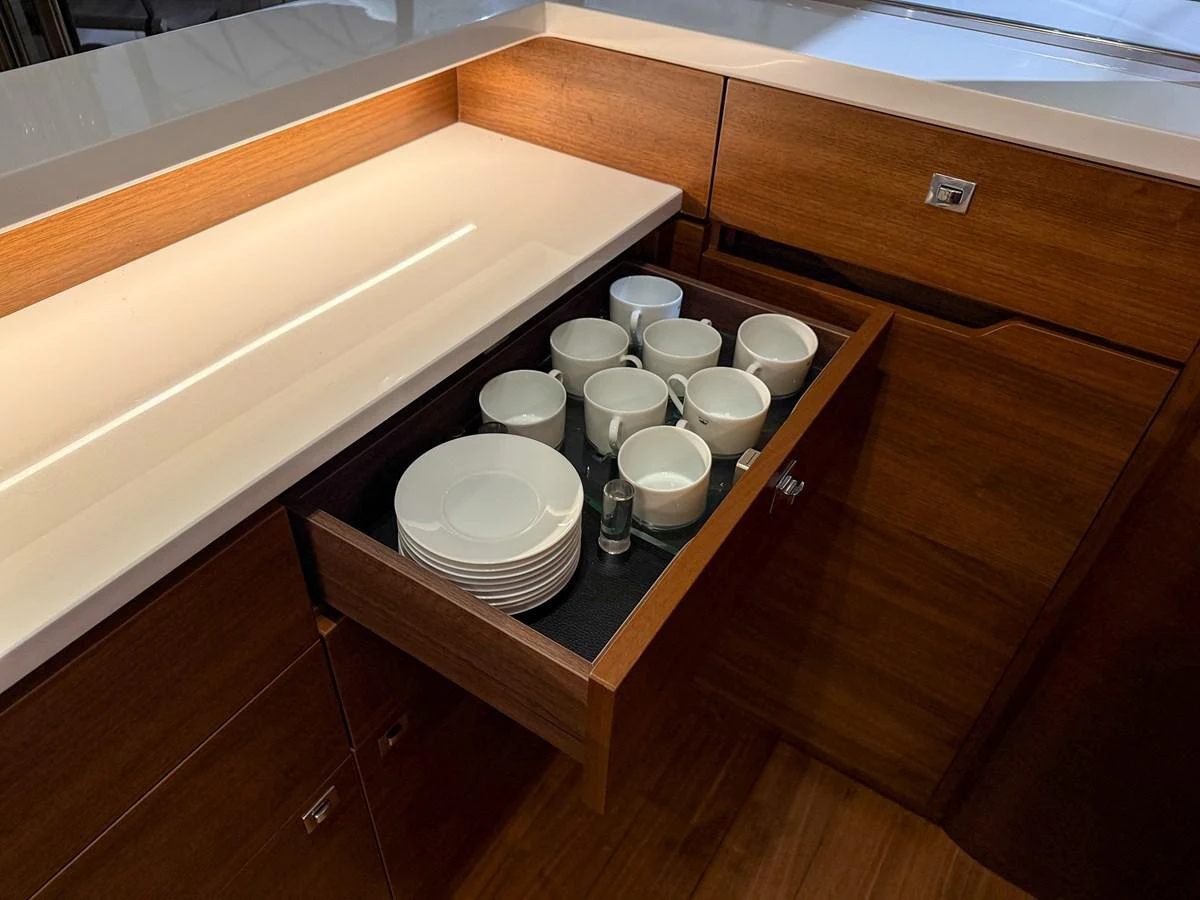 The image shows a neatly organized drawer in the yacht's galley, containing cups and plates. aboard PRINCESS 70 Yacht for Sale