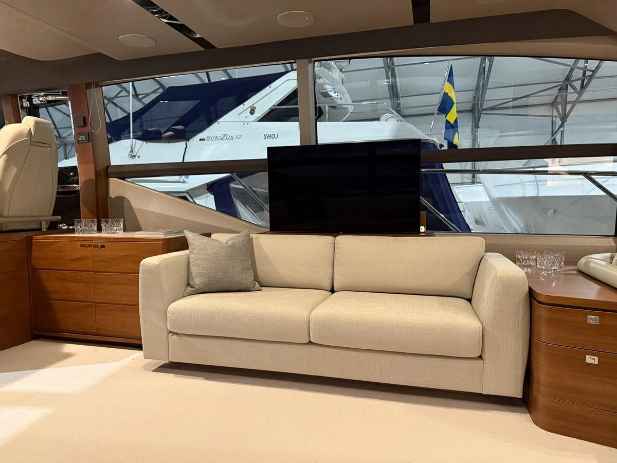 The salon features a comfortable beige sofa with a view of the marina through large windows. aboard PRINCESS 70 Yacht for Sale