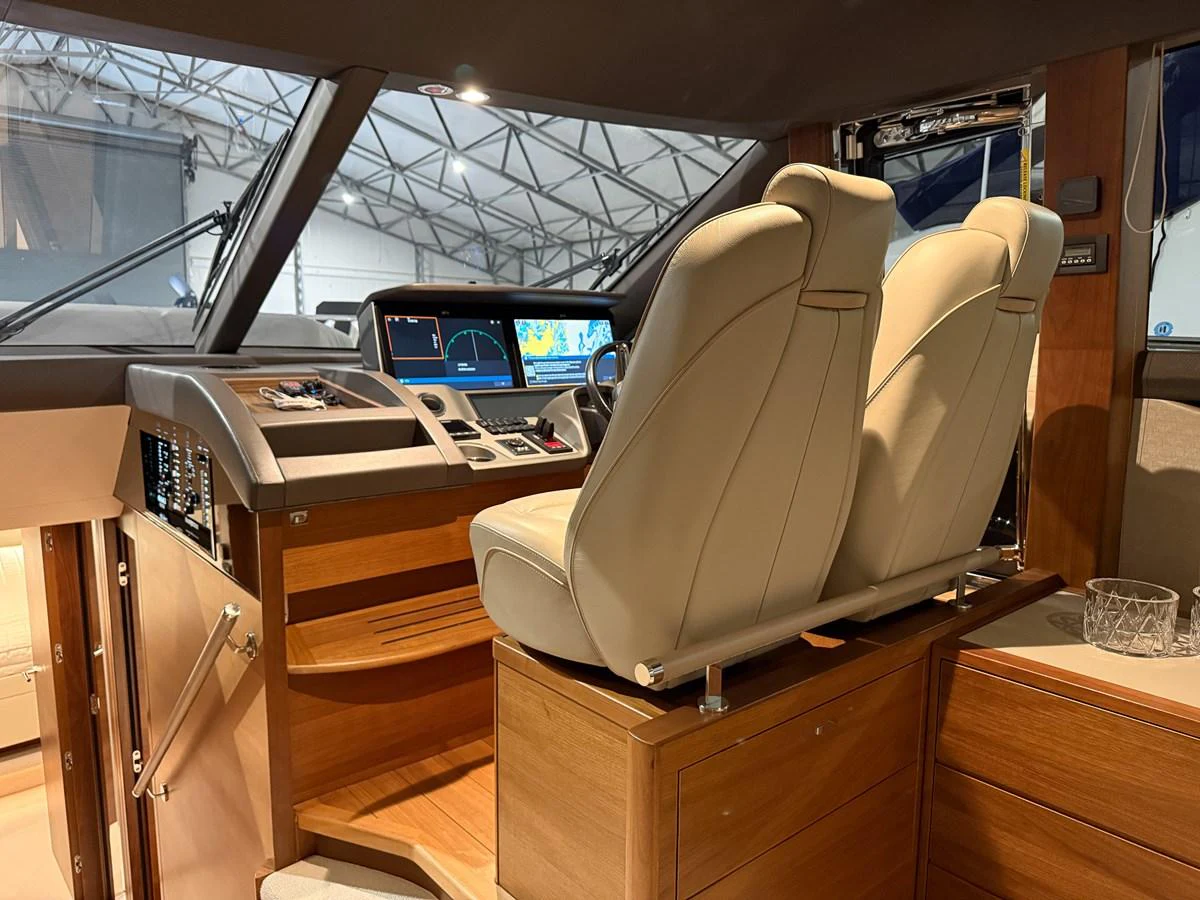 The helm station features plush seating and advanced navigation equipment, set within a stylish wooden interior. aboard PRINCESS 70 Yacht for Sale