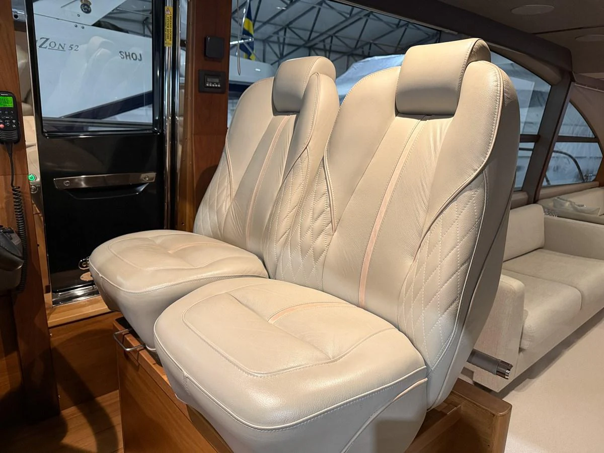 The image showcases the luxurious helm seating area with plush, cream-colored leather seats. aboard PRINCESS 70 Yacht for Sale