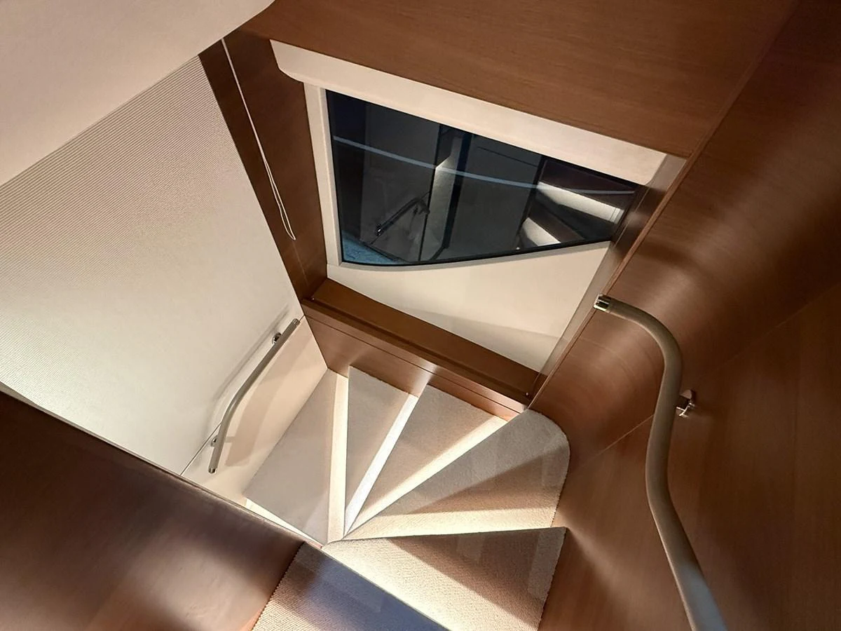 A beautifully designed interior staircase with elegant wooden finishes and soft lighting. aboard PRINCESS 70 Yacht for Sale
