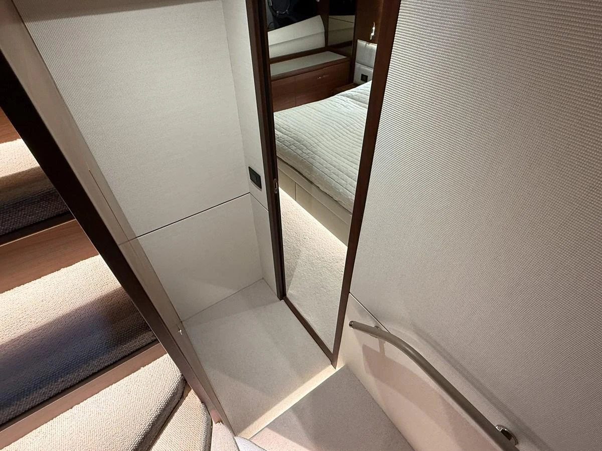 A well-lit stairway leads to a cozy stateroom with a neatly made bed. aboard PRINCESS 70 Yacht for Sale