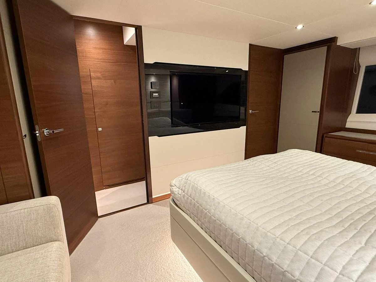 A luxurious stateroom featuring a large bed, modern wood paneling, and a flat-screen TV. aboard PRINCESS 70 Yacht for Sale