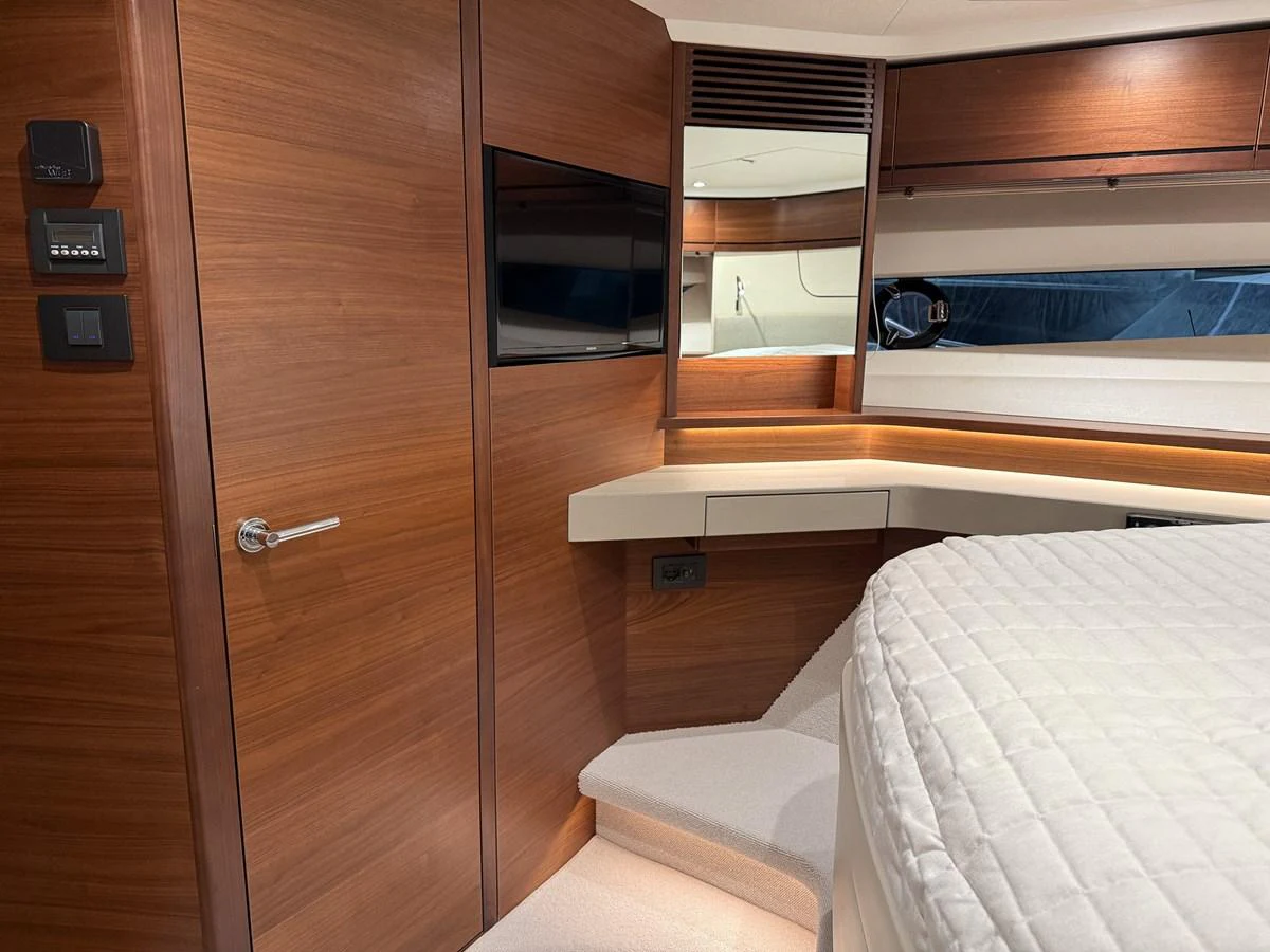 The stateroom features warm wood paneling, a mounted TV, and a cozy bed with a quilted cover. aboard PRINCESS 70 Yacht for Sale