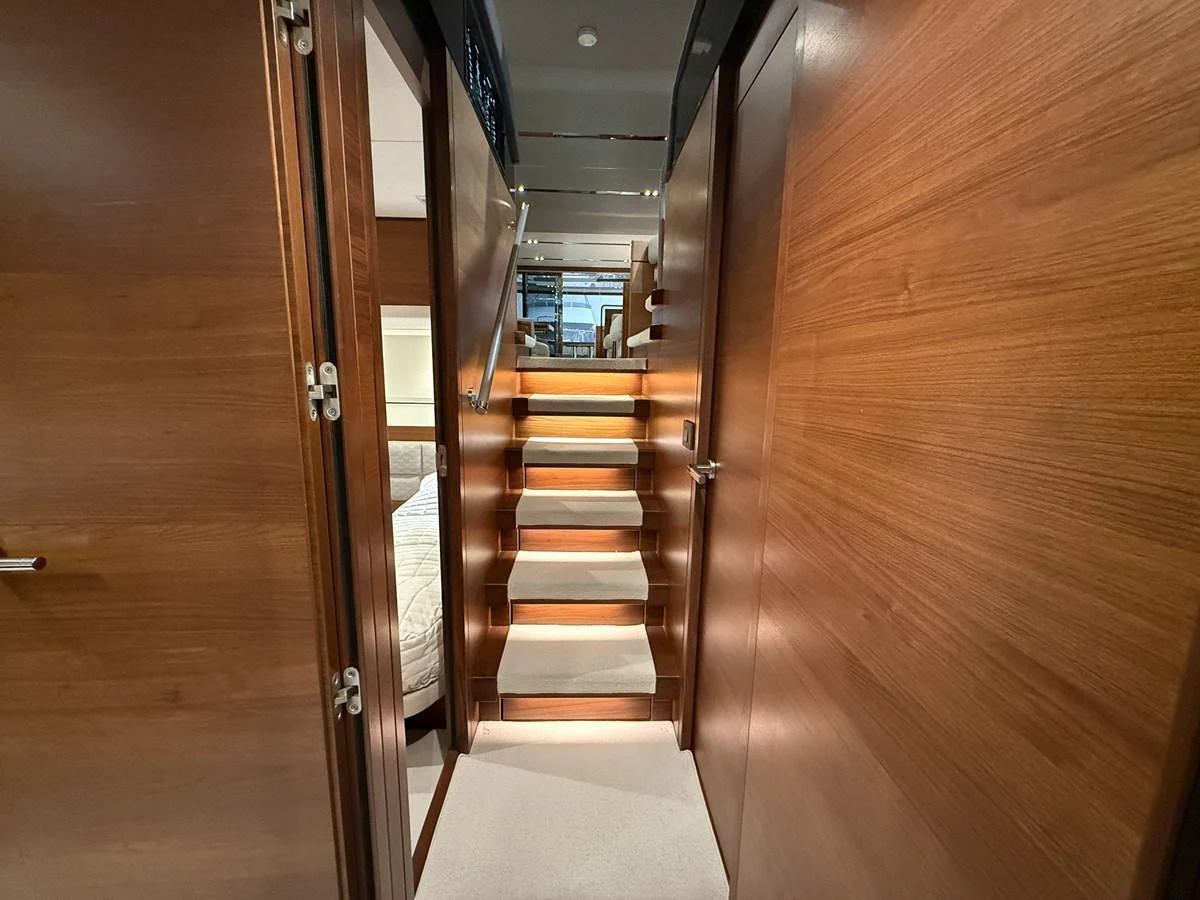 A well-lit hallway with wooden finishes and a staircase leading to the upper deck. aboard PRINCESS 70 Yacht for Sale