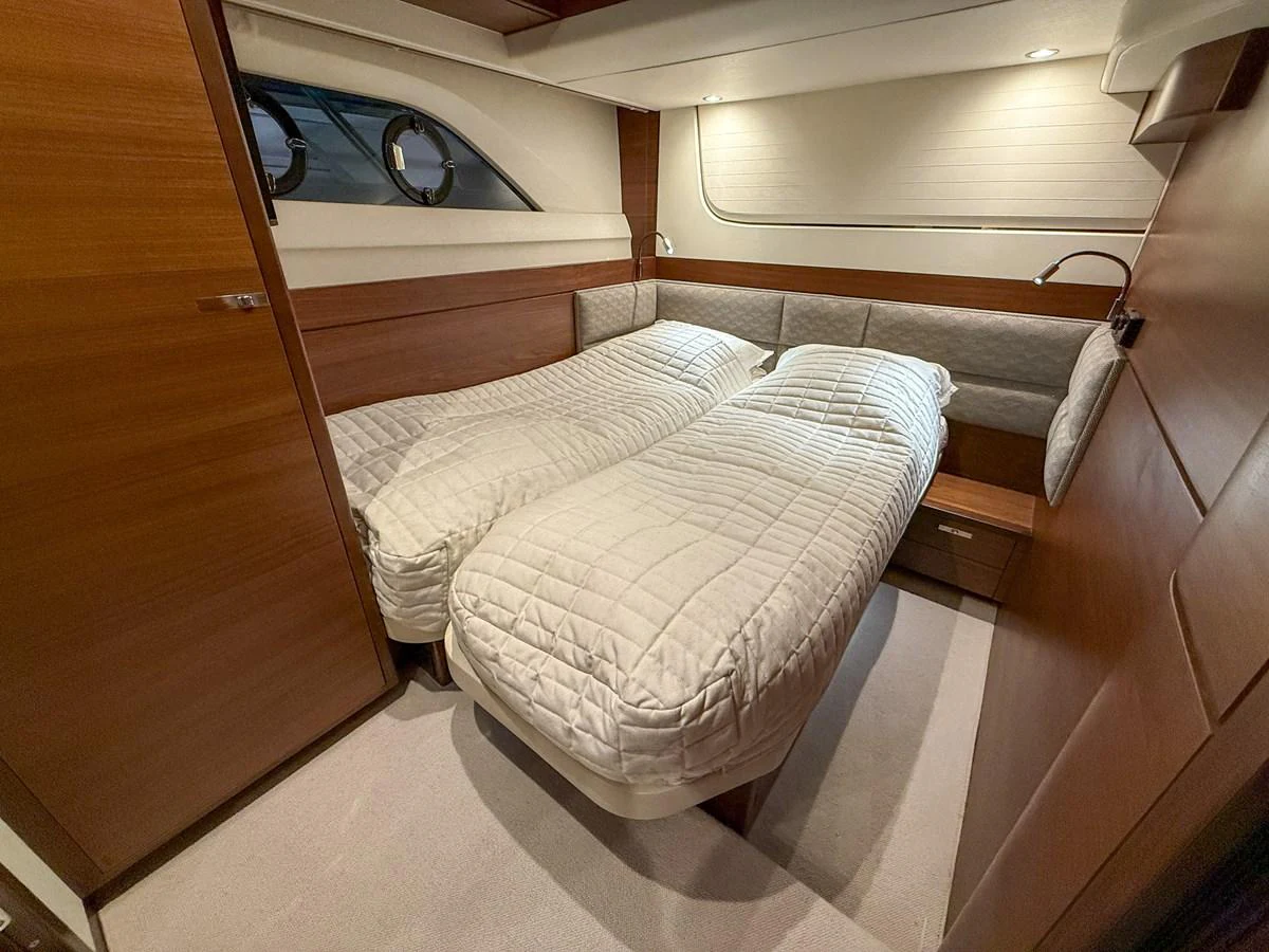 The guest stateroom features twin beds with elegant bedding and warm wood finishes. aboard PRINCESS 70 Yacht for Sale