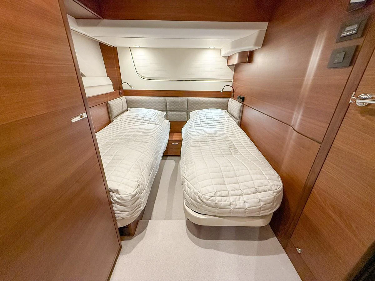 This cozy twin stateroom features two single beds with elegant wooden paneling and soft lighting. aboard PRINCESS 70 Yacht for Sale