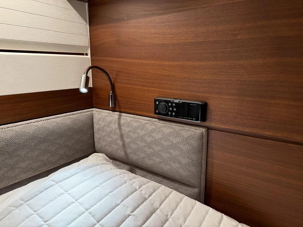 A cozy cabin corner with a reading light and a control panel above a cushioned bed. aboard PRINCESS 70 Yacht for Sale