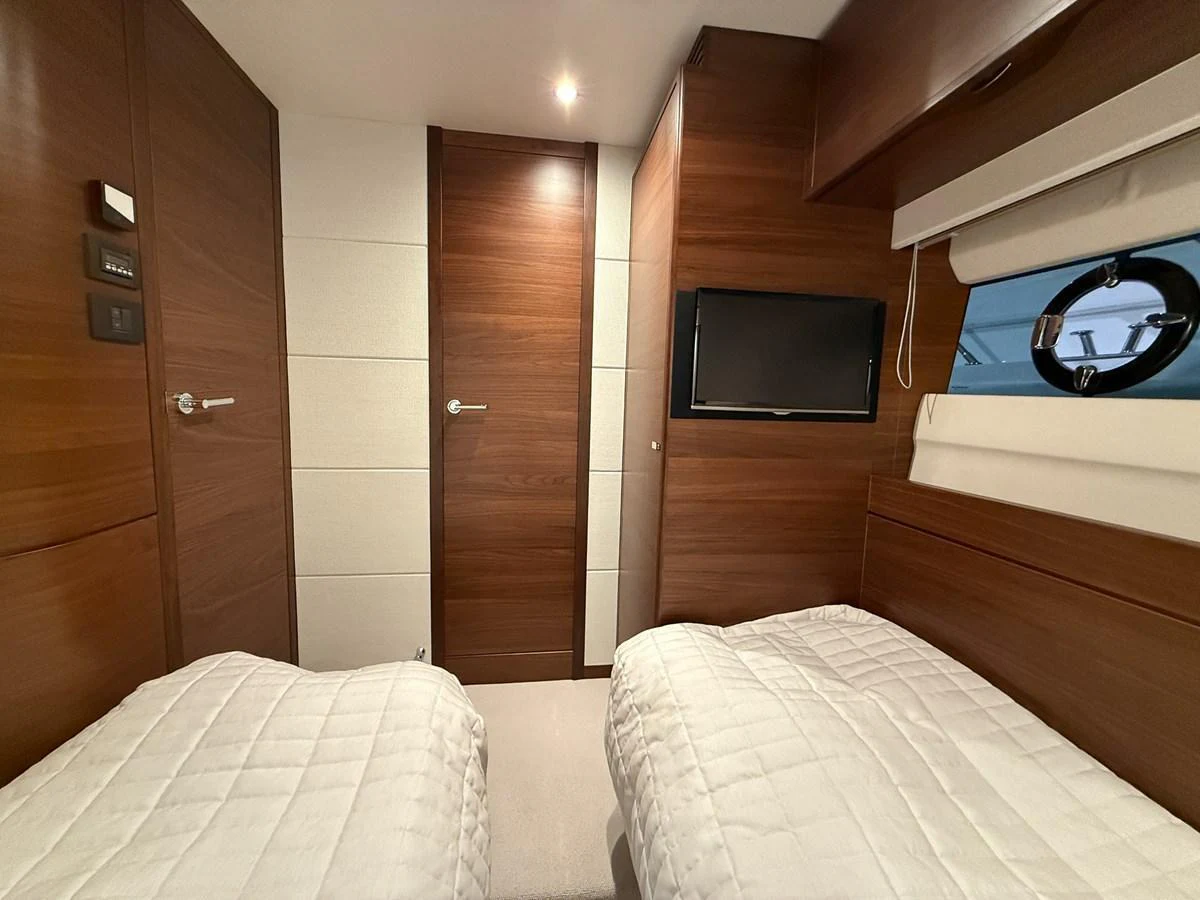 The guest stateroom features twin beds, rich wood paneling, and a flat-screen TV for a comfortable stay. aboard PRINCESS 70 Yacht for Sale