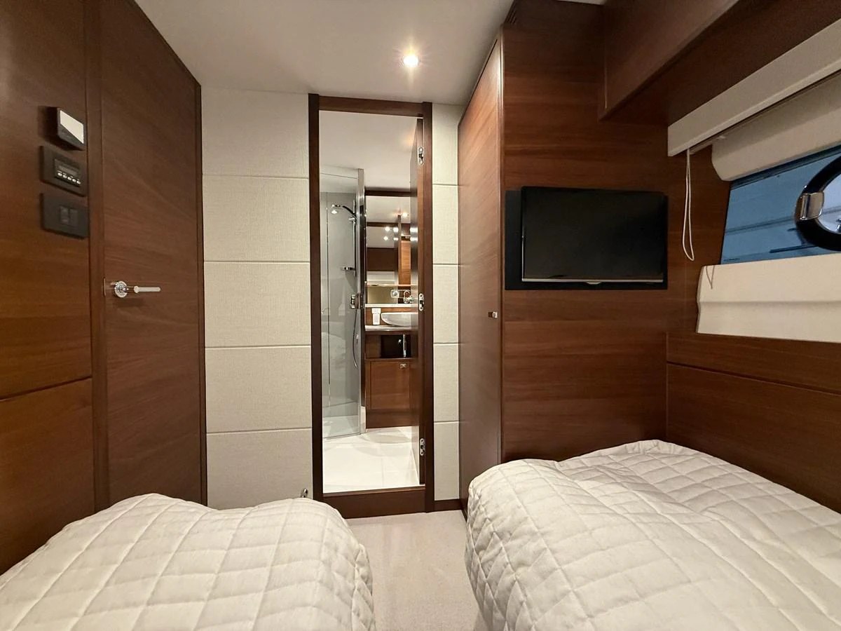 The guest stateroom features twin beds, a wall-mounted TV, and an ensuite bathroom. aboard PRINCESS 70 Yacht for Sale
