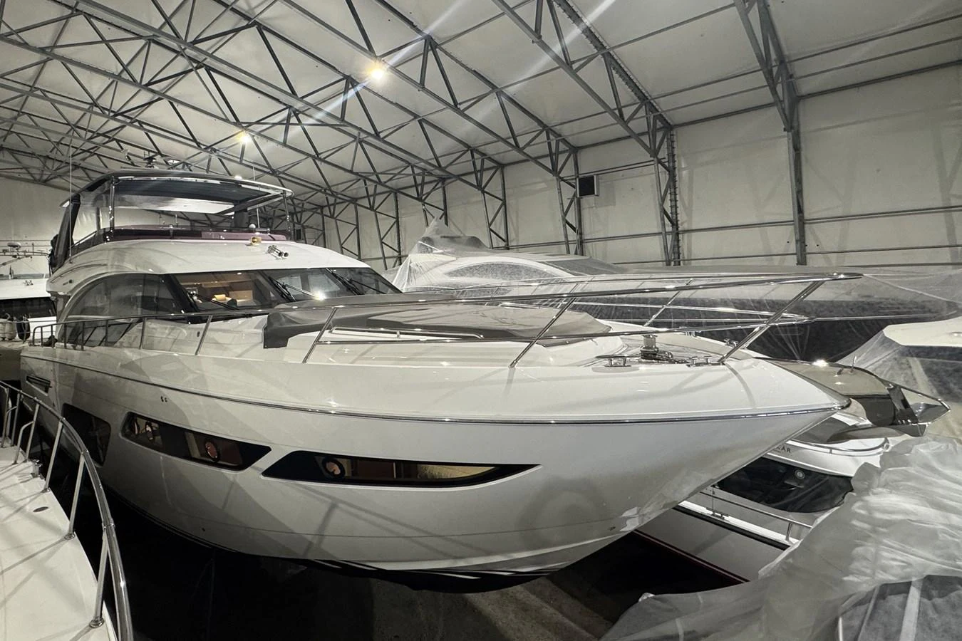A sleek yacht is showcased in an indoor storage facility, highlighting its modern design and pristine condition. aboard PRINCESS 70 Yacht for Sale