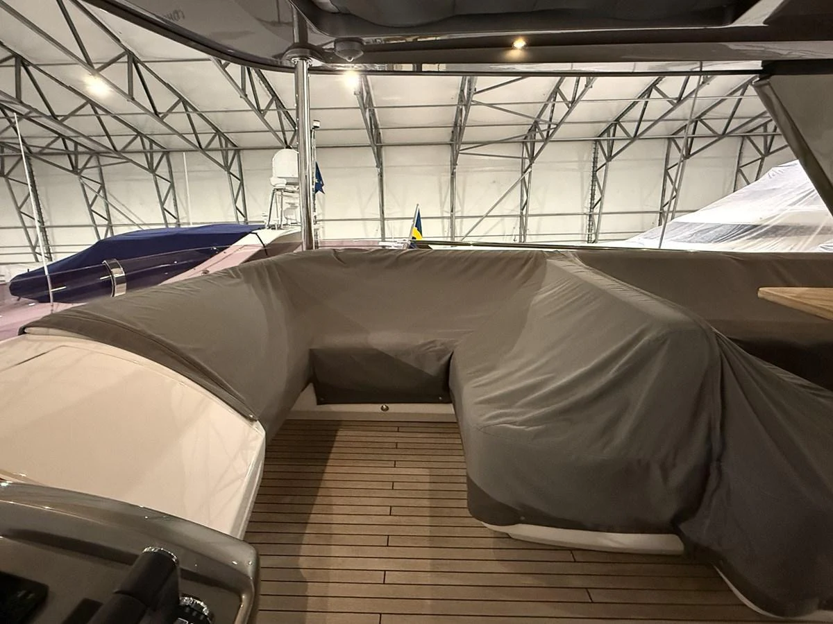 The yacht's interior features a covered seating area with a wooden floor, currently stored in a sheltered environment. aboard PRINCESS 70 Yacht for Sale