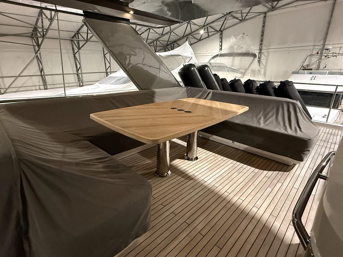 The aft deck features a sleek wooden table and covered seating, perfect for outdoor dining and relaxation. aboard PRINCESS 70 Yacht for Sale