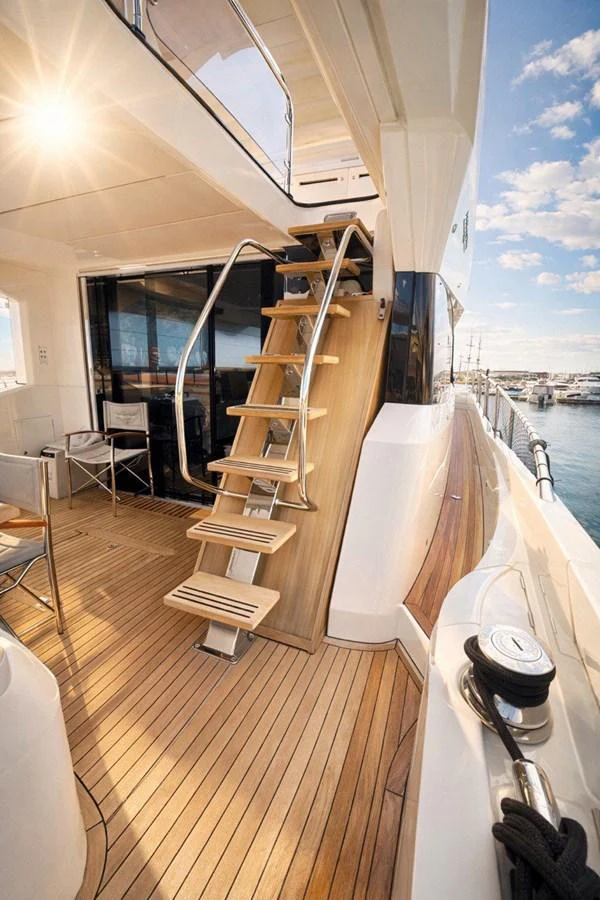 The yacht's aft deck features a stylish staircase leading to the upper deck, with a view of the marina in the background. aboard SUNSEEKER 66 MANHATTAN Yacht for Sale