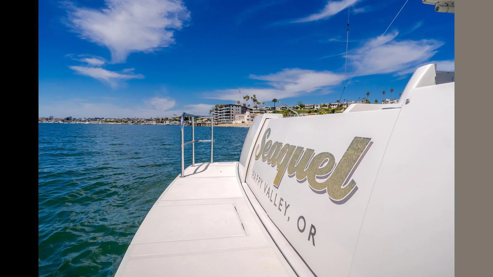 The yacht's stern is shown with a view of the water and distant shoreline under a clear blue sky. aboard SEAQUEL Yacht for Sale