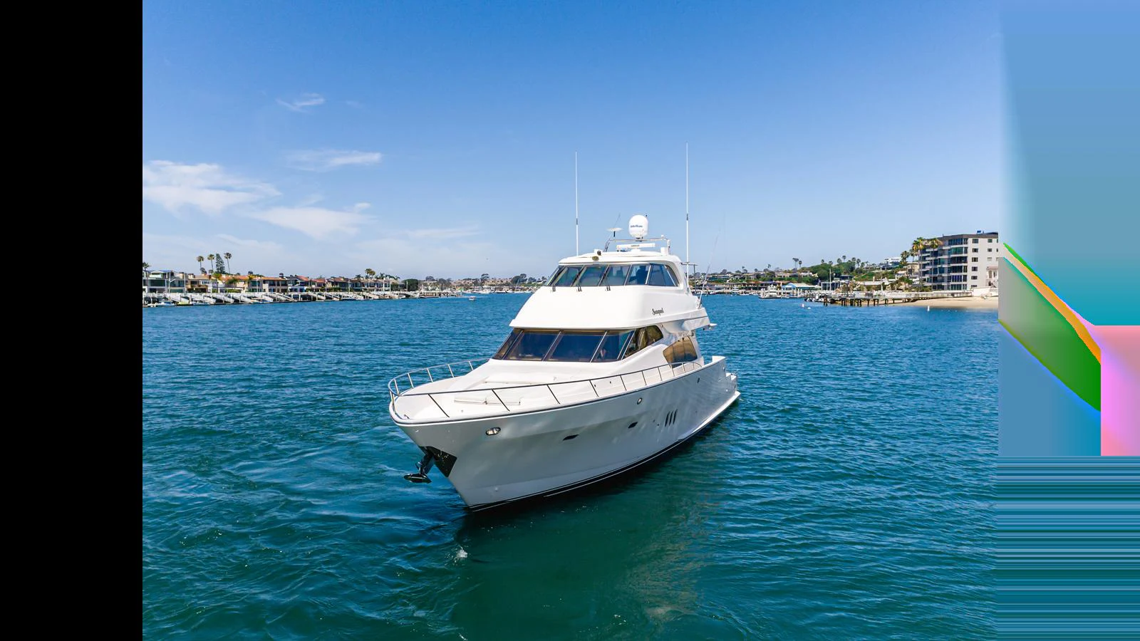 A sleek yacht cruises on calm blue waters near a coastal town. aboard SEAQUEL Yacht for Sale