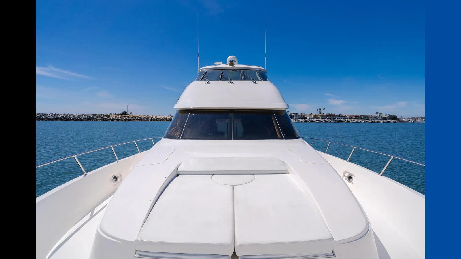 A sleek yacht is shown from the bow, highlighting its modern design against a clear blue sky and calm waters. aboard SEAQUEL Yacht for Sale