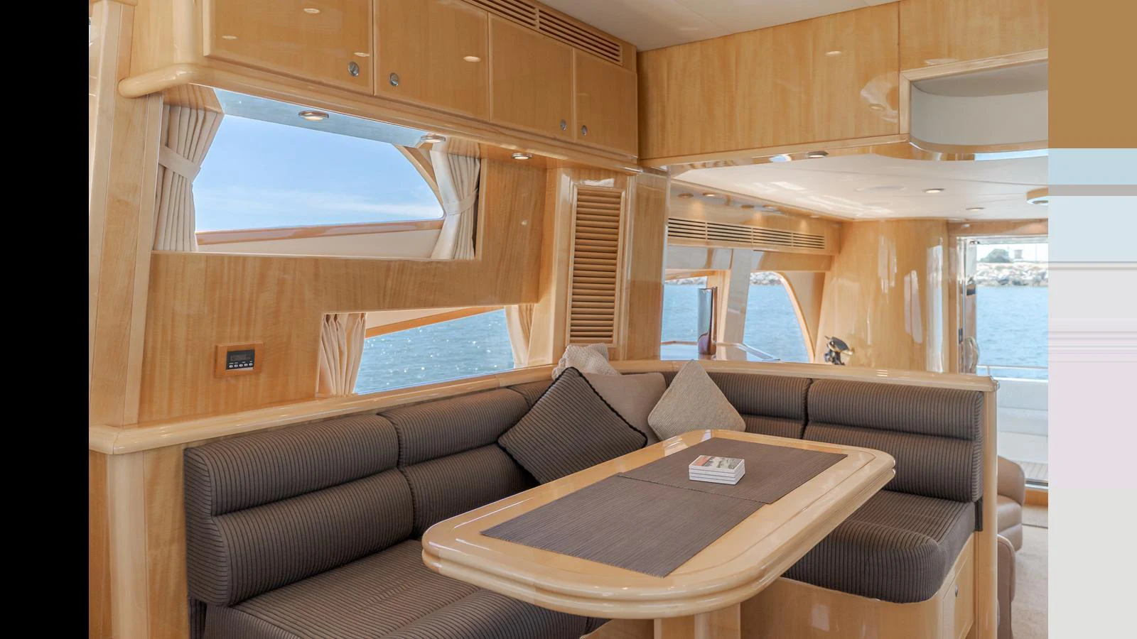 The salon features a comfortable seating area with a dining table, surrounded by large windows offering scenic views. aboard SEAQUEL Yacht for Sale