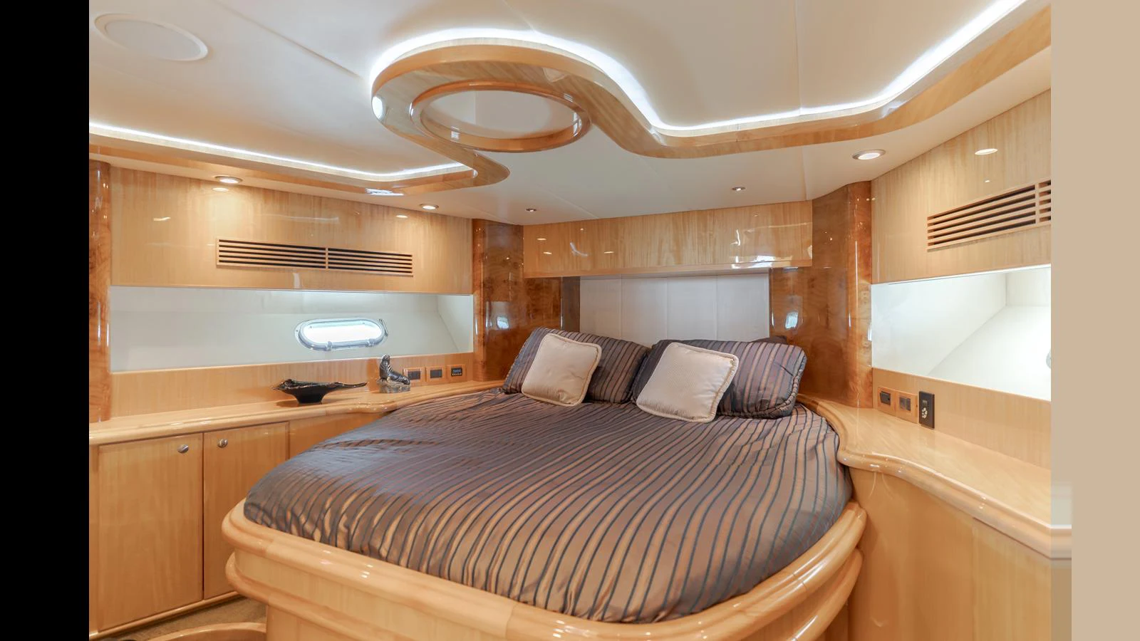 A luxurious stateroom featuring a large bed with elegant wood paneling and ambient lighting. aboard SEAQUEL Yacht for Sale