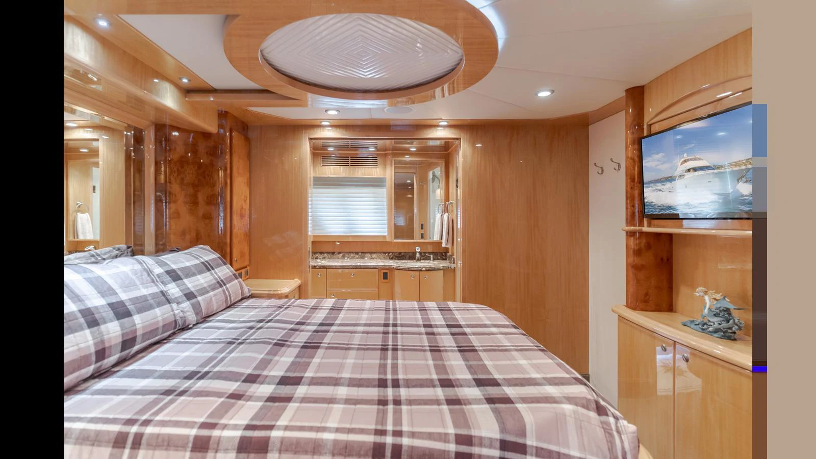 The stateroom features a cozy bed with a plaid bedspread, warm wood finishes, and a mounted TV. aboard SEAQUEL Yacht for Sale