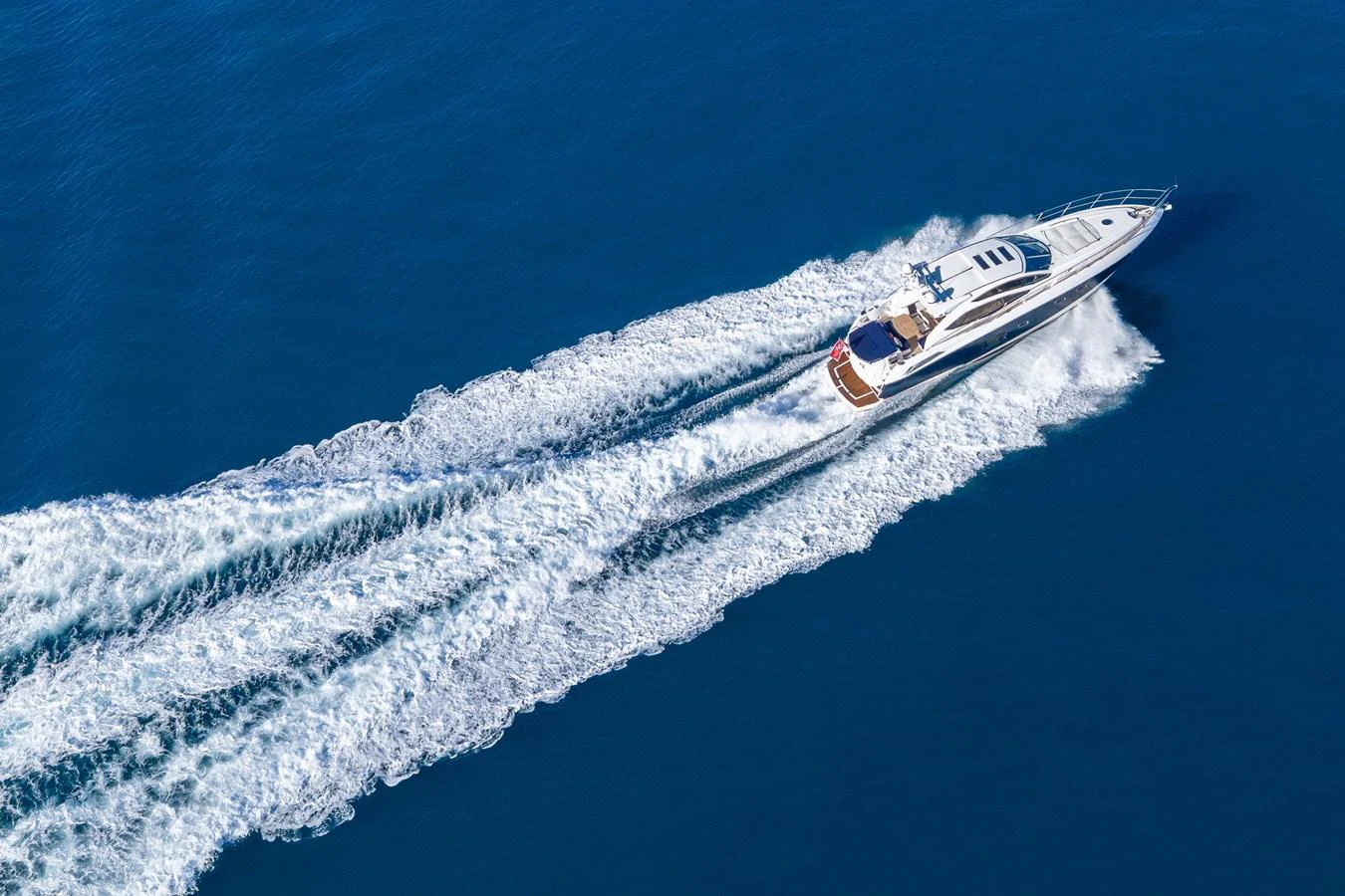 A sleek yacht cruises swiftly through the open water, leaving a trail of white wake behind. aboard M/Y MIEL Yacht for Sale
