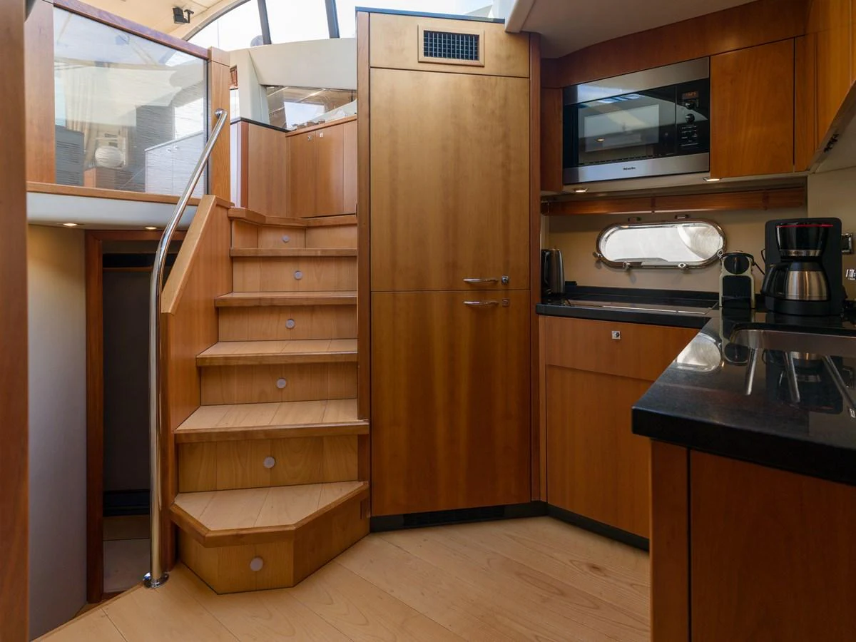 The yacht's galley features modern appliances and warm wooden cabinetry, creating a cozy and functional space. aboard M/Y MIEL Yacht for Sale