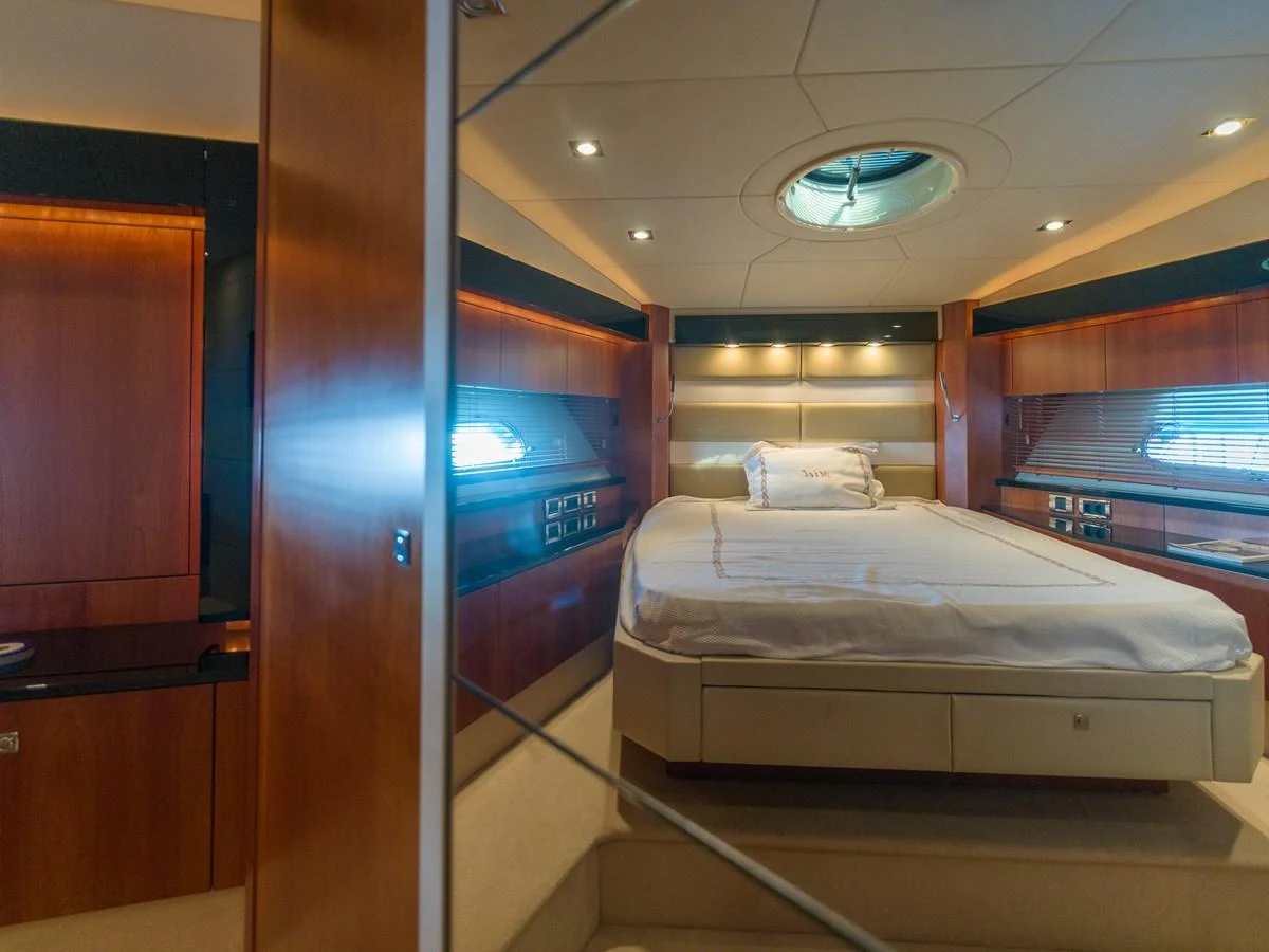 The stateroom features a luxurious bed with elegant wood paneling and ample natural light. aboard M/Y MIEL Yacht for Sale