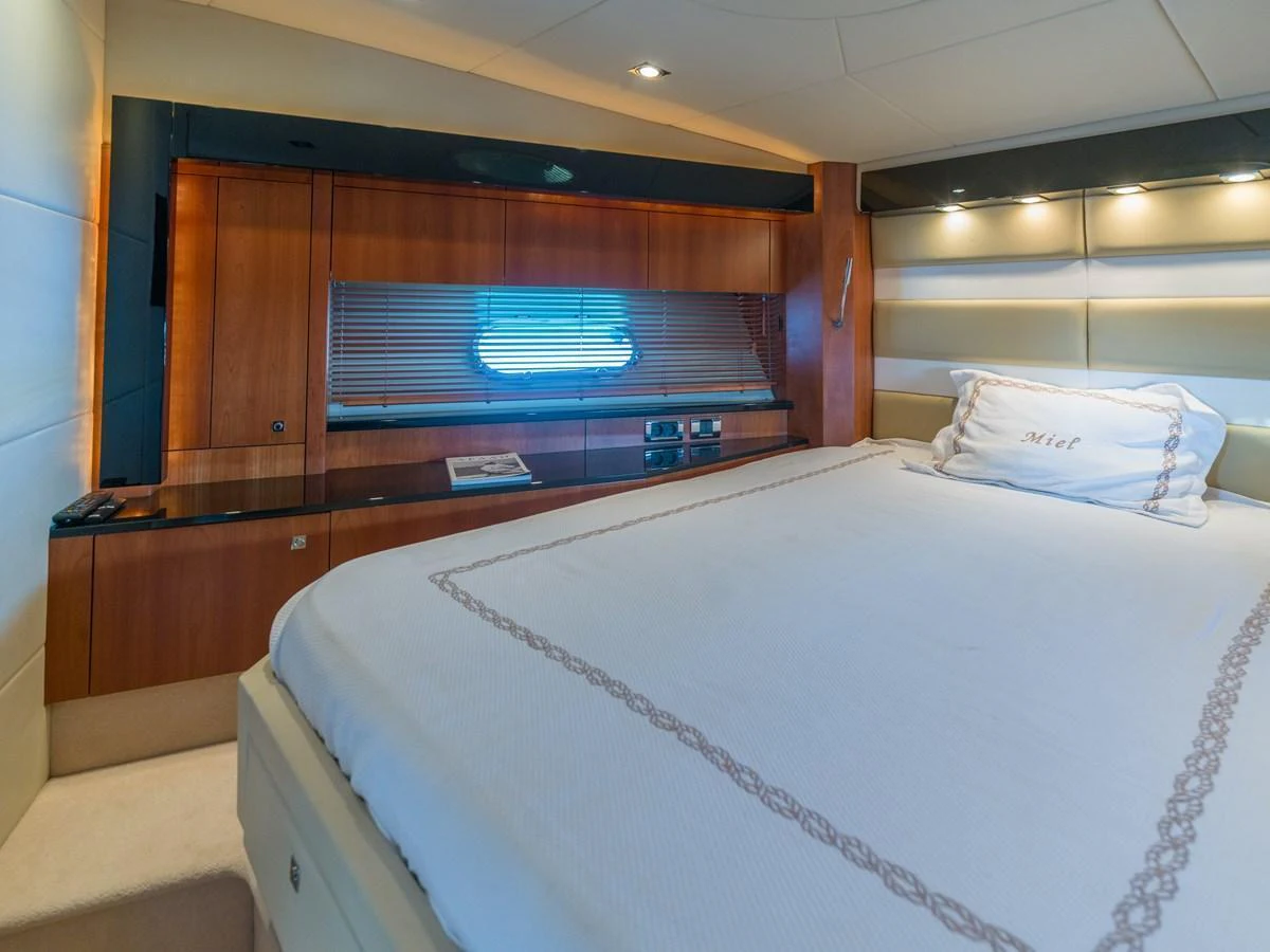 The stateroom features a luxurious bed with elegant wood paneling and ambient lighting. aboard M/Y MIEL Yacht for Sale