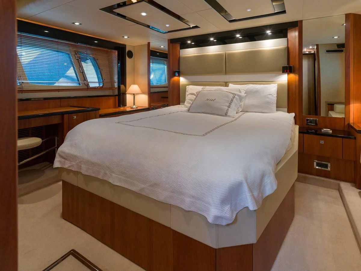 The master stateroom features a luxurious bed with elegant wood finishes and ample natural light. aboard M/Y MIEL Yacht for Sale