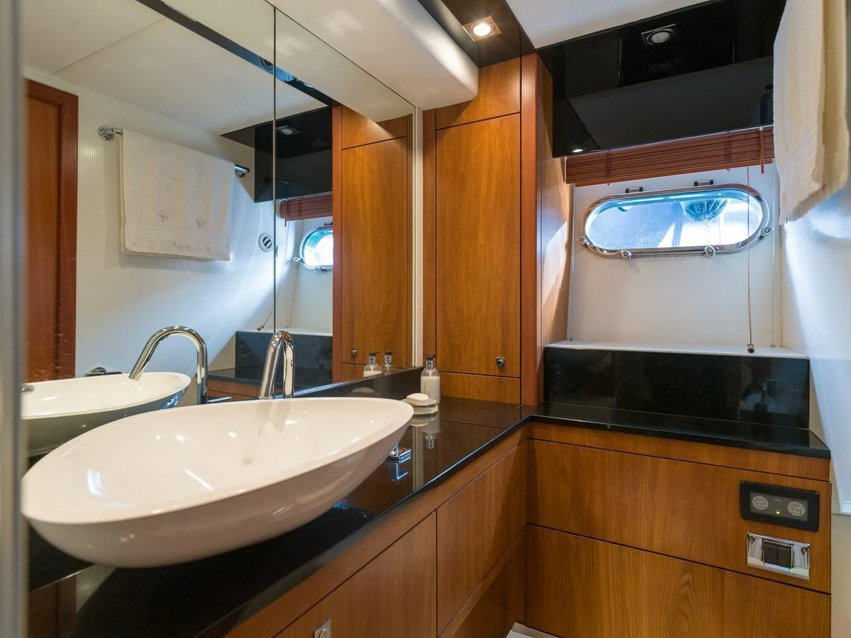 The yacht's bathroom features elegant wood cabinetry, a sleek vessel sink, and a large mirror, creating a luxurious and functional space. aboard M/Y MIEL Yacht for Sale