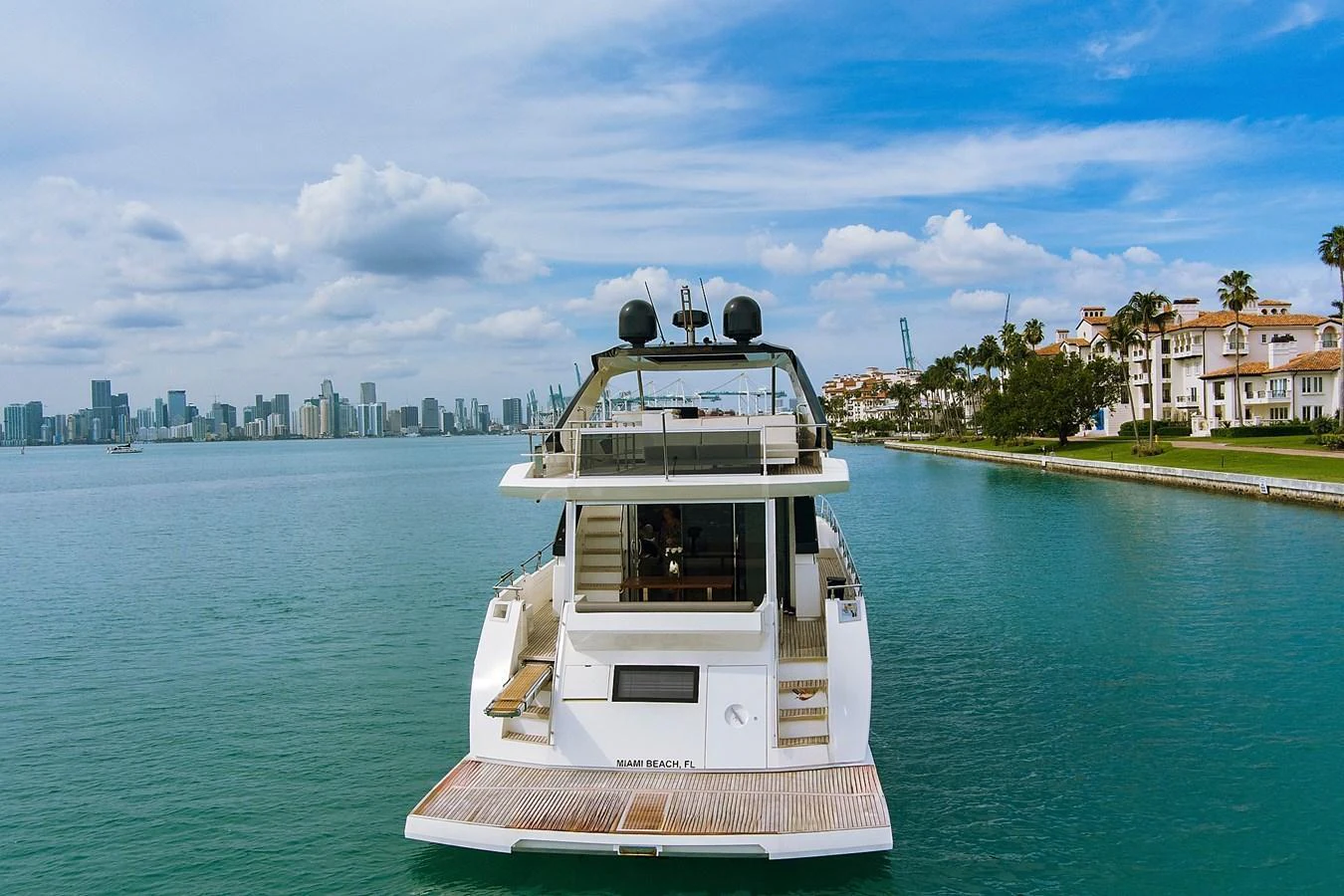 The yacht is docked in a serene waterfront setting with a view of the city skyline in the background. aboard JESSEA Yacht for Sale