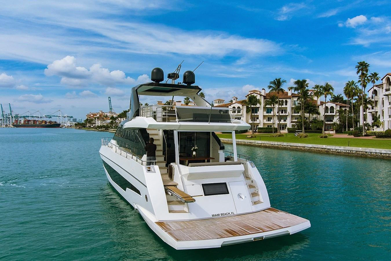 A sleek and modern yacht cruising near a luxurious waterfront community. aboard JESSEA Yacht for Sale