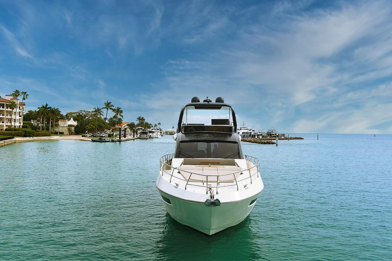 A sleek yacht is anchored in calm, turquoise waters with a picturesque coastal backdrop. aboard JESSEA Yacht for Sale