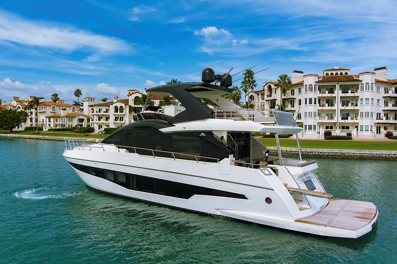 A sleek, modern yacht is docked near a luxurious waterfront community. aboard JESSEA Yacht for Sale