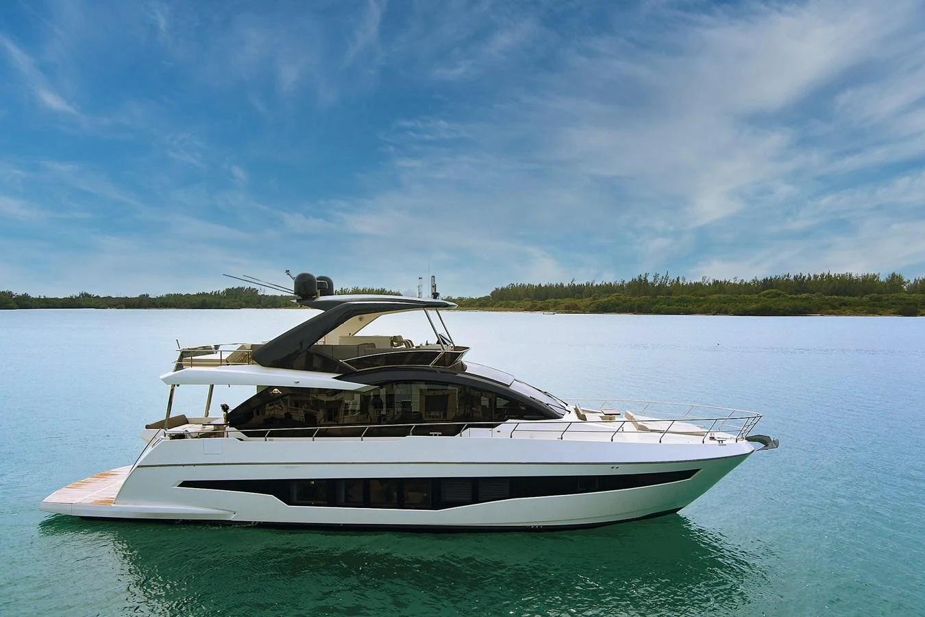 A sleek, modern yacht glides gracefully on calm waters under a clear blue sky. aboard JESSEA Yacht for Sale