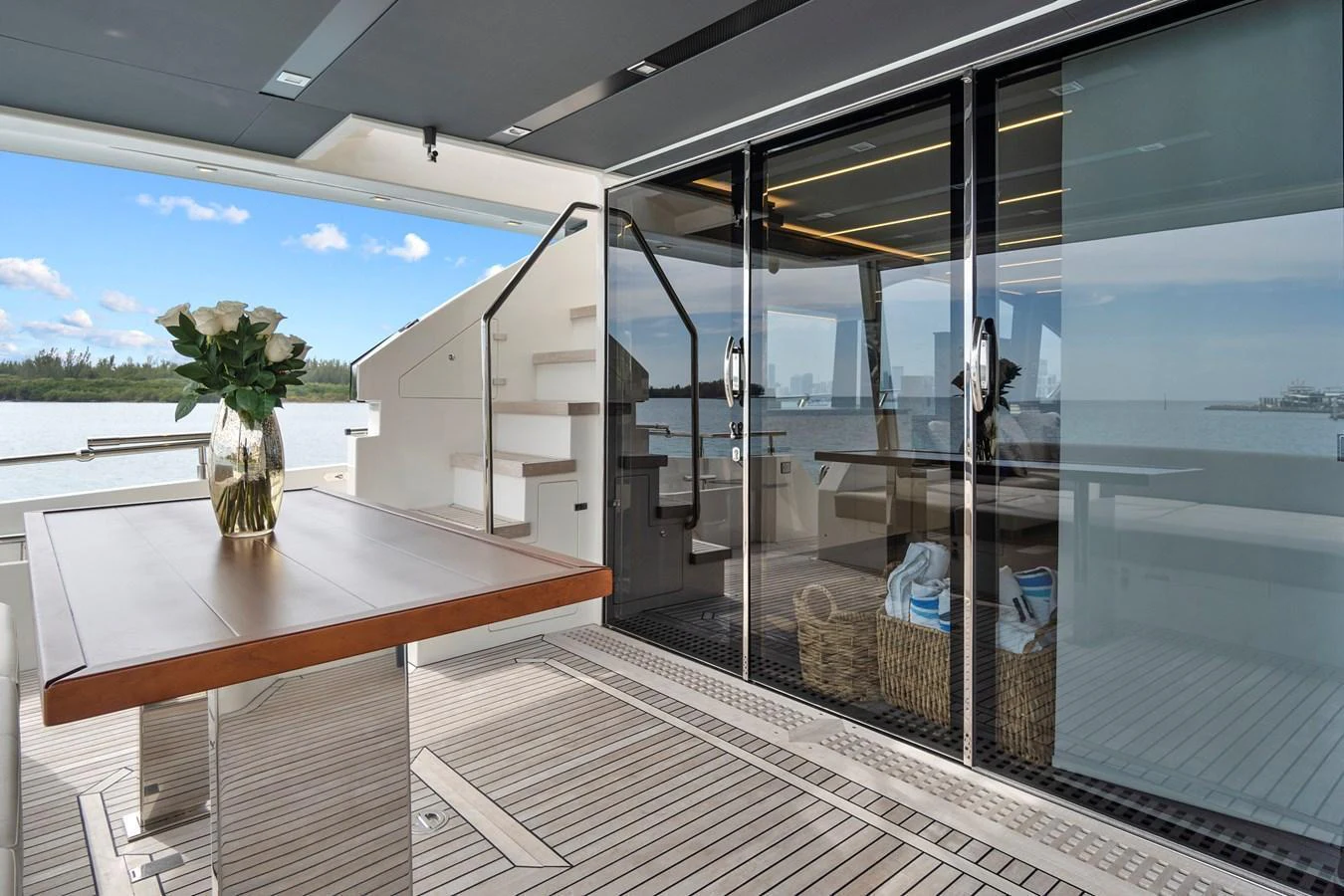 The aft deck features a sleek dining area with a polished table and a beautiful view of the water. aboard JESSEA Yacht for Sale