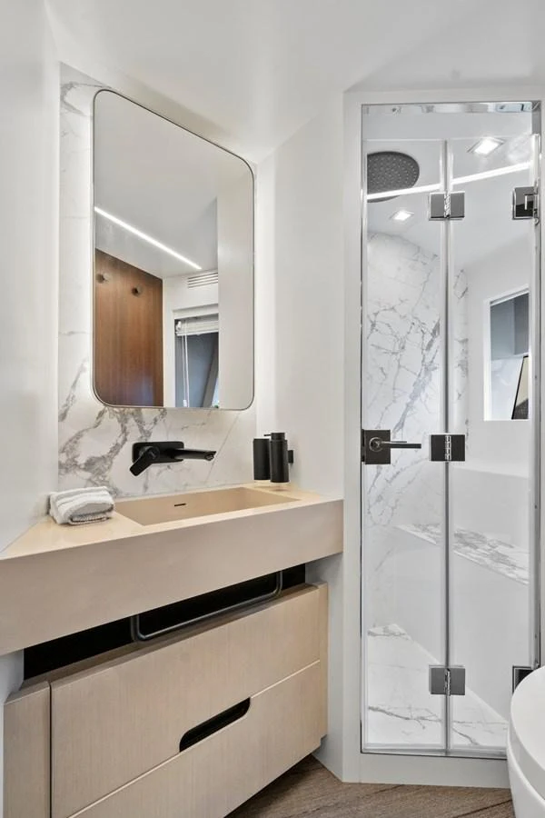 A sleek and modern yacht bathroom featuring a marble sink and a glass-enclosed shower. aboard JESSEA Yacht for Sale