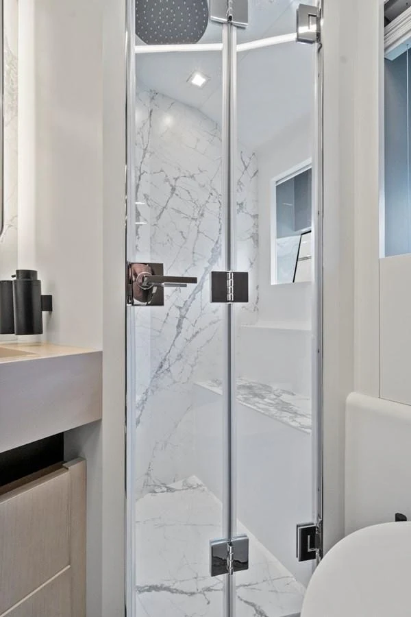 A sleek and modern yacht bathroom with a glass-enclosed shower and marble accents. aboard JESSEA Yacht for Sale