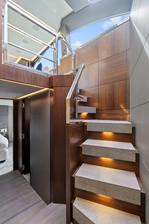 A modern yacht interior featuring a sleek wooden staircase with ambient lighting. aboard JESSEA Yacht for Sale