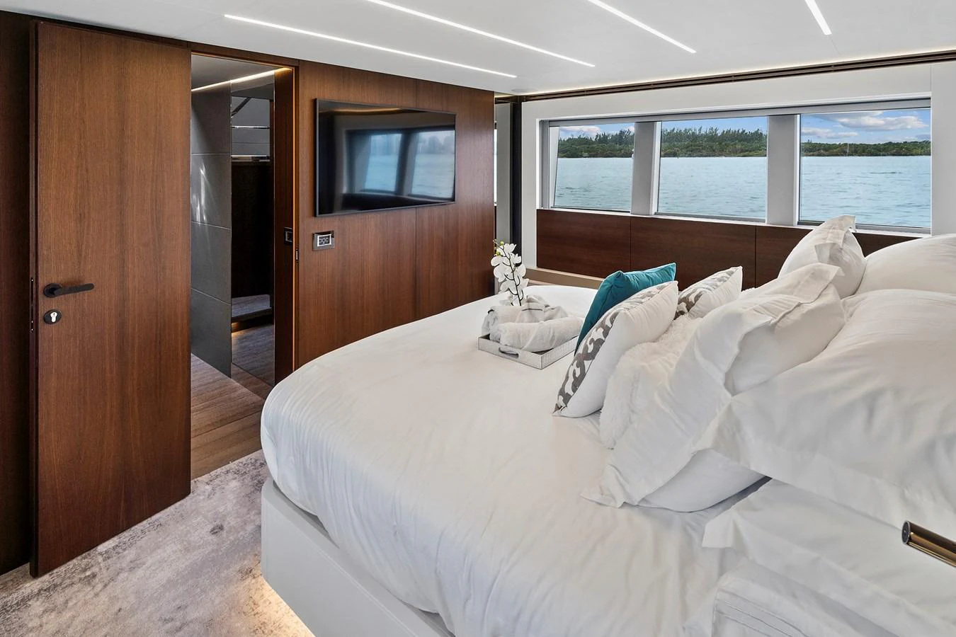 The stateroom features a luxurious bed with a view of the sea through large windows. aboard JESSEA Yacht for Sale