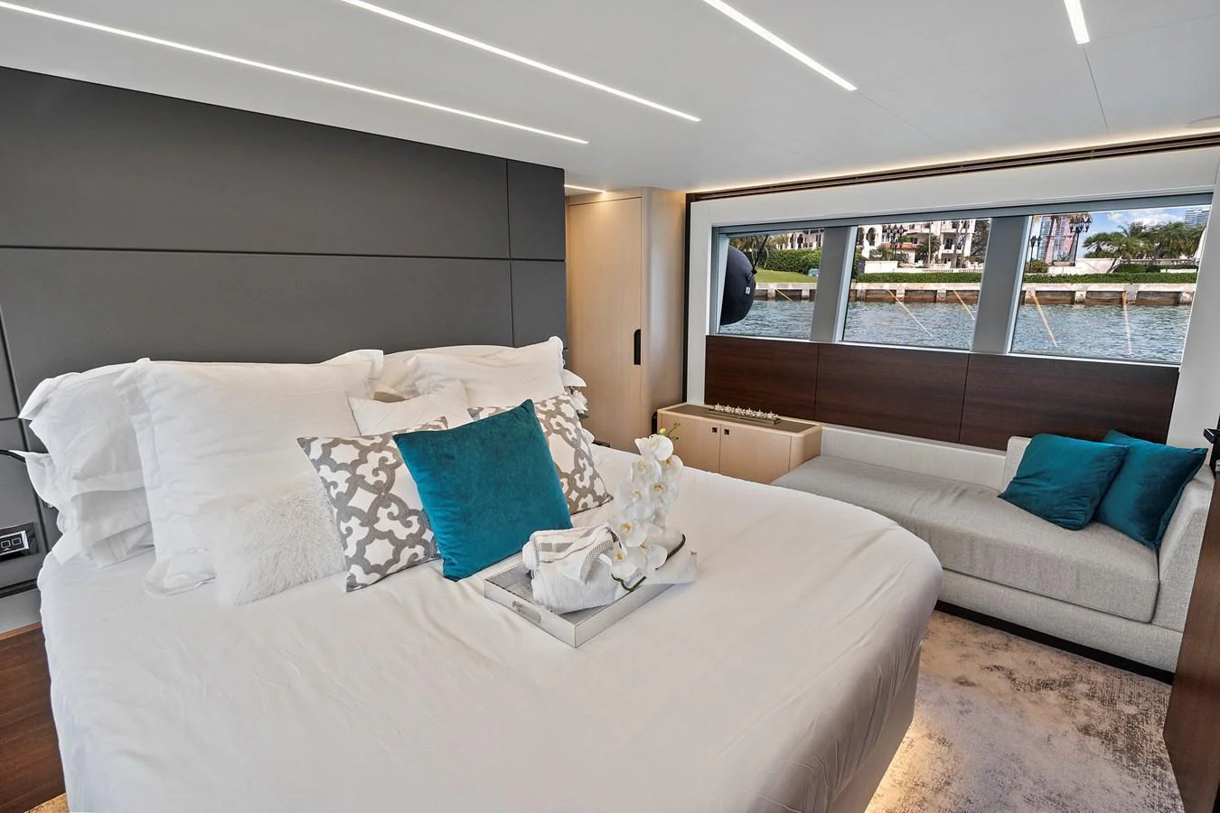 The stateroom features a plush bed with elegant linens and a cozy seating area by large windows offering a scenic view. aboard JESSEA Yacht for Sale