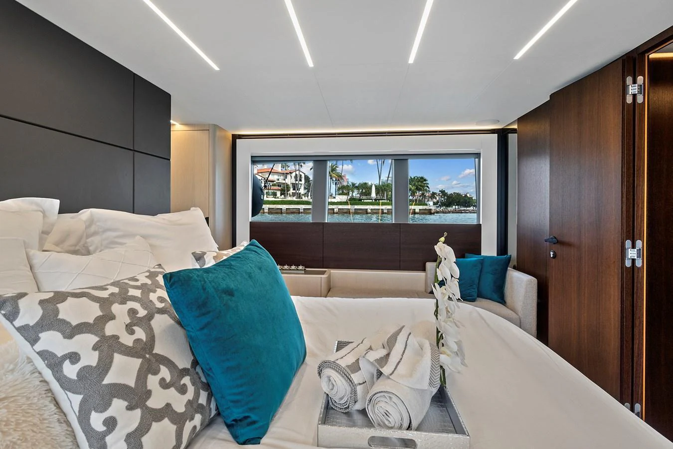 A luxurious stateroom featuring a large bed with plush pillows and a view of the water through wide windows. aboard JESSEA Yacht for Sale