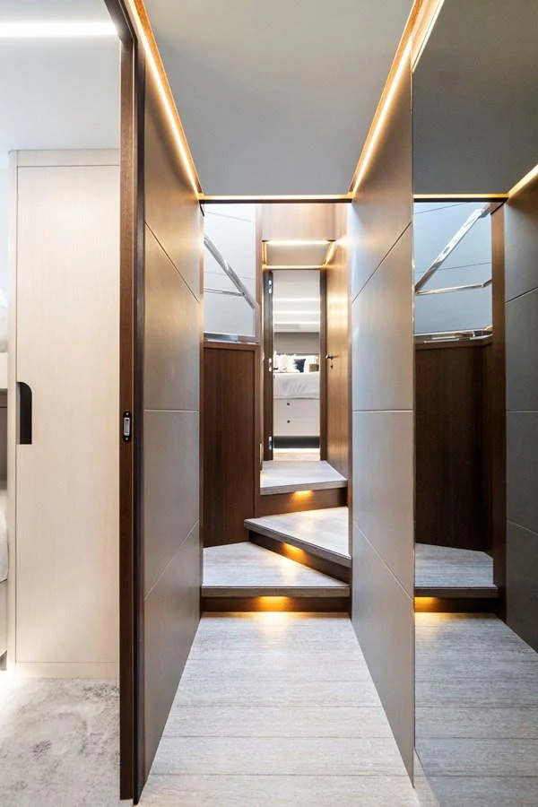 The image showcases a modern and sleek interior hallway with elegant lighting and wooden accents. aboard JESSEA Yacht for Sale