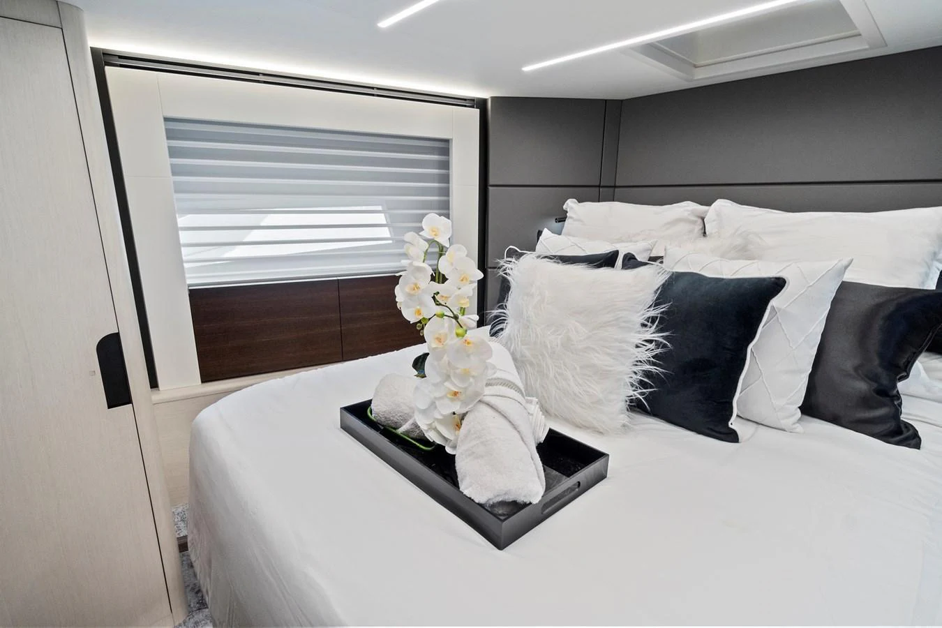 A luxurious stateroom featuring a plush bed adorned with elegant pillows and a decorative tray with flowers. aboard JESSEA Yacht for Sale