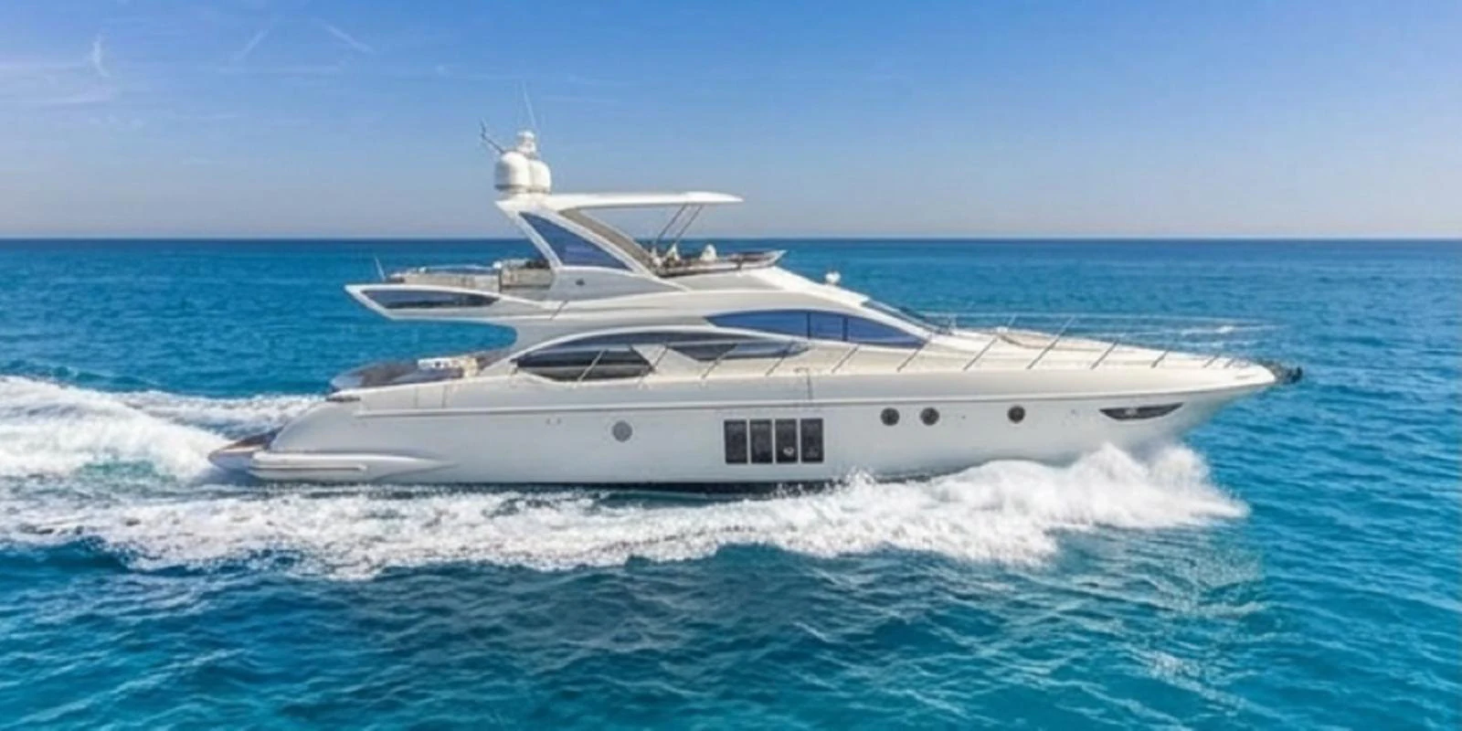 A sleek and modern yacht cruising through clear blue waters under a bright sky. aboard TARKAN Yacht for Sale