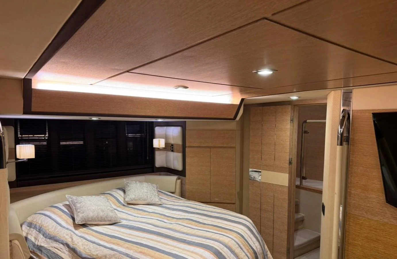 The stateroom features a cozy bed with striped bedding and warm wooden finishes. aboard TARKAN Yacht for Sale