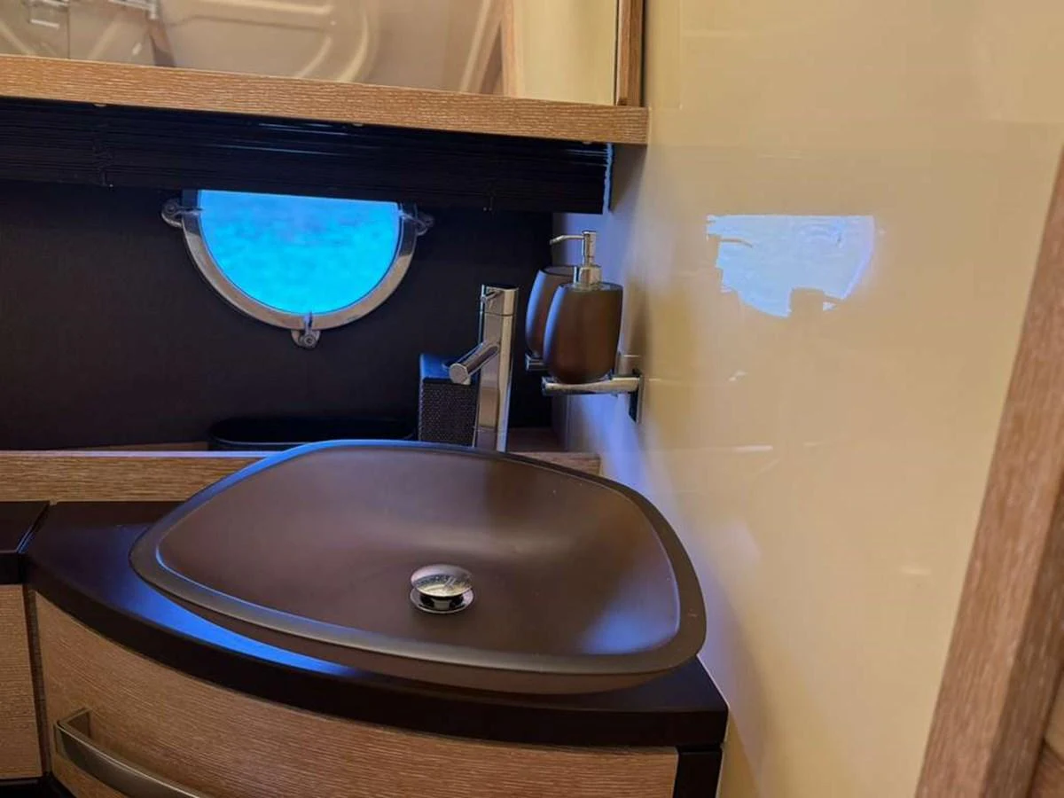 A stylish yacht bathroom with a modern sink and a porthole window. aboard TARKAN Yacht for Sale