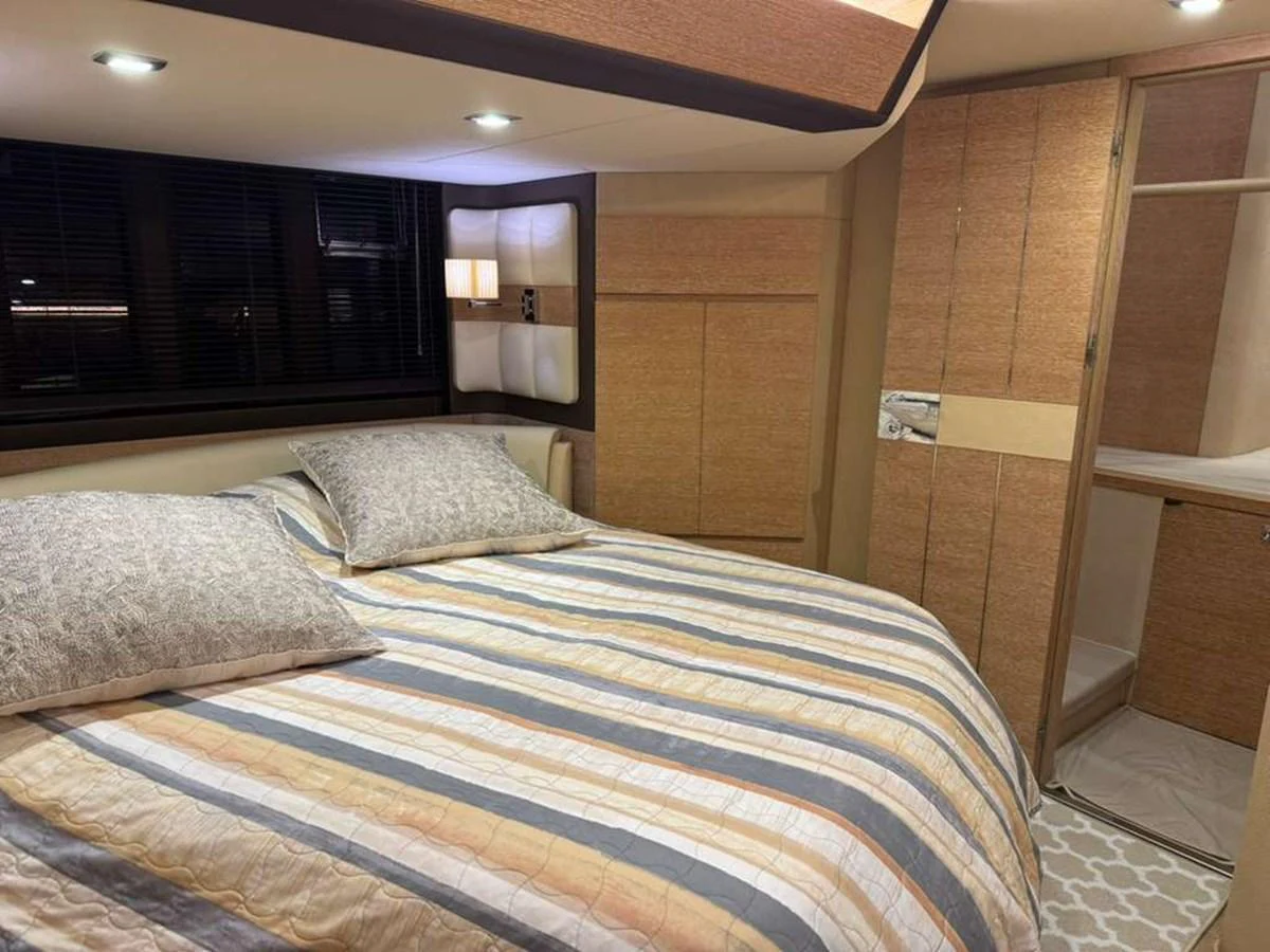 The stateroom features a cozy bed with striped bedding and ample storage space. aboard TARKAN Yacht for Sale