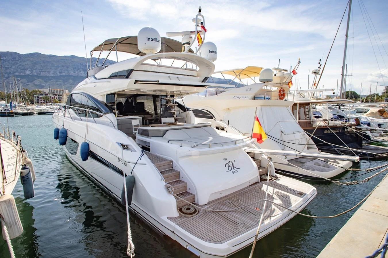 The yacht is docked at a marina, showcasing its elegant aft deck and sleek design. aboard BK ONE Yacht for Sale